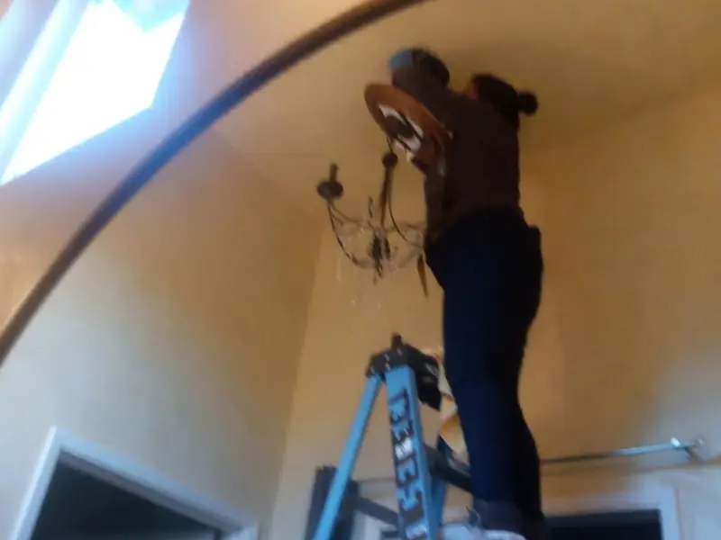 Electrician installing a chandelier in a Blanchard residence